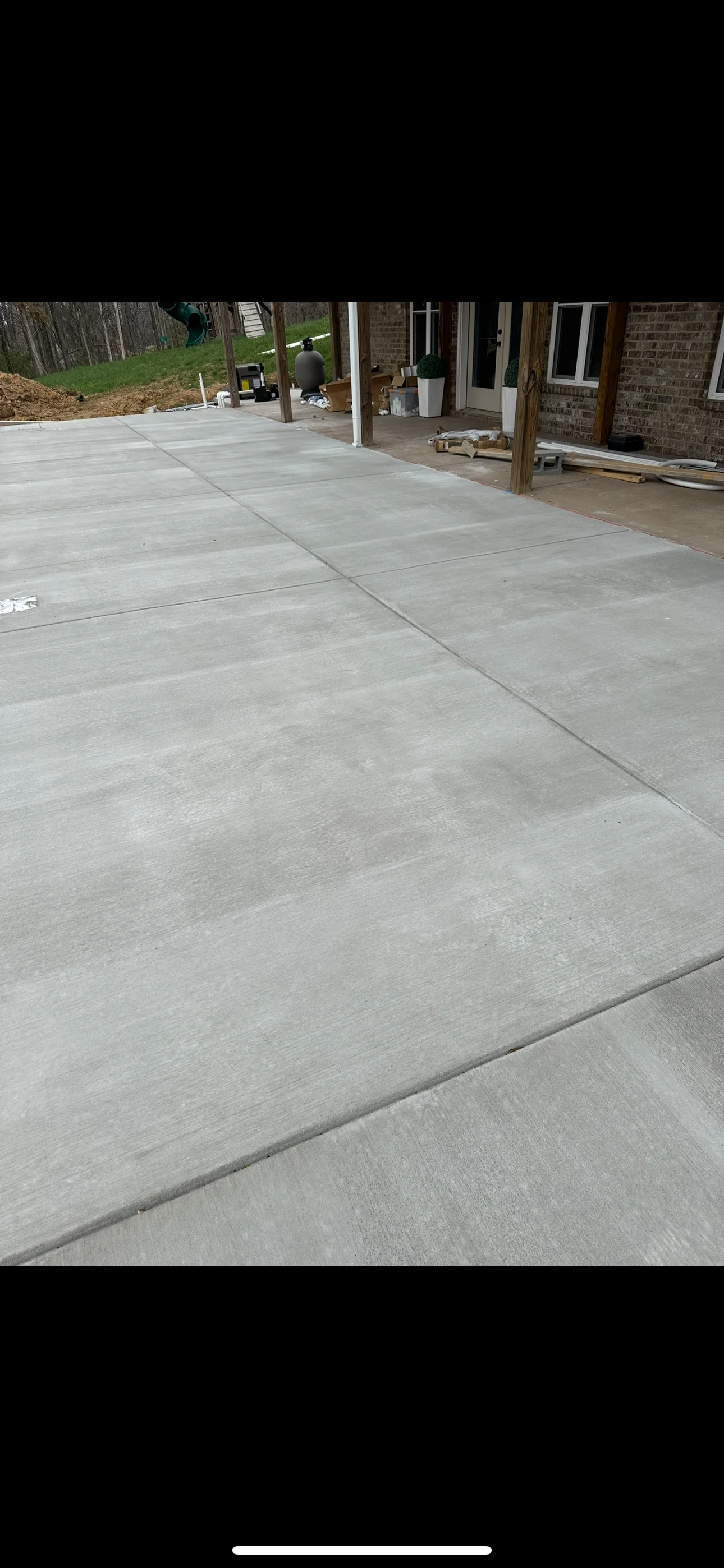 Finished concrete patio with control joints and wooden post supports at residential home