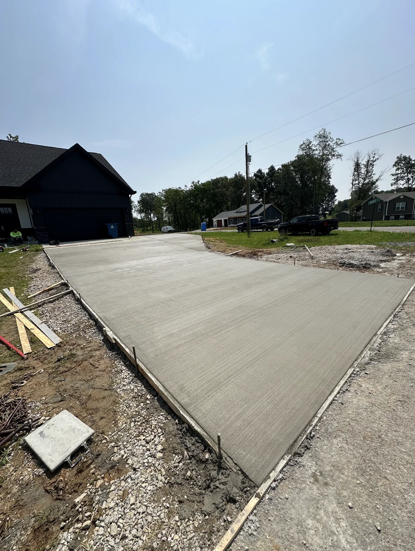 Newly poured concrete driveway with broom finish and wooden edge forms on residential property