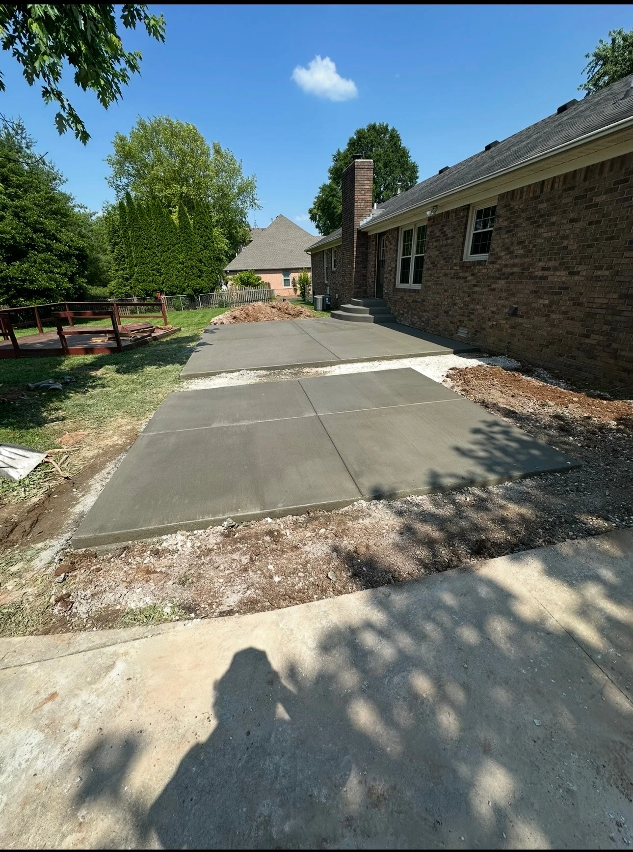 New concrete patio with control joints installed beside brick home with mulch landscaping