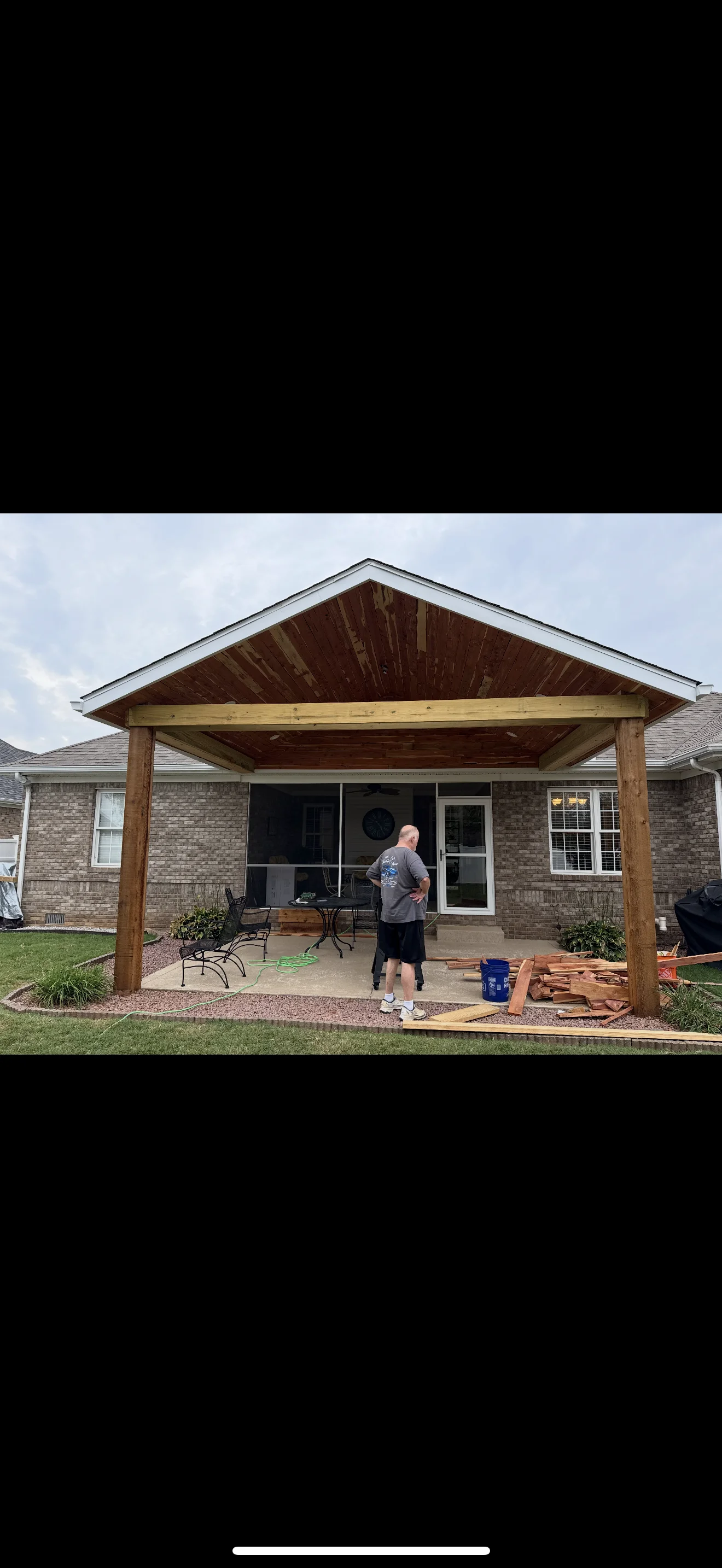 Wooden gabled patio cover with exposed beams attached to brick home in Lancaster